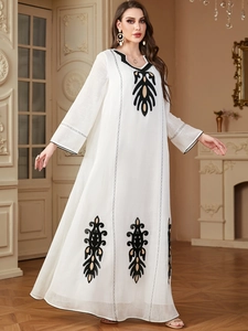 Gros plan détaillé des broderies ethniques noires sur cette robe caftan blanche