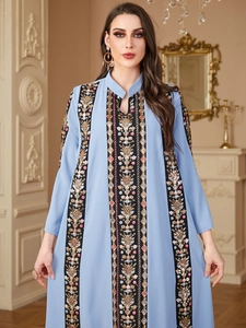 Detailed close-up of intricate gold and floral embroidery on a light blue kaftan dress