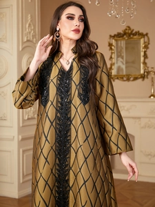 Detail of bronze satin long dress with black geometric prints and sequin embroidery on bodice