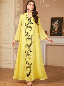 Detail of elegant yellow robe dress featuring intricate black embroidery and lace cuffs