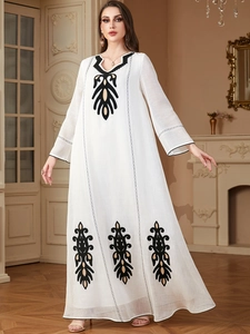 Détail de la robe longue blanche à manches longues avec broderie élégante noire et dorée