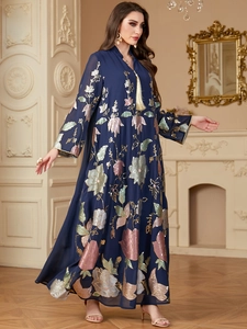 Detail of navy blue maxi dress featuring gold embroidery and cream-colored tassels
