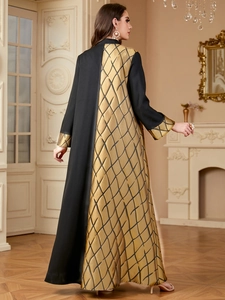 Vue détaillée d'une abaya élégante avec motifs dorés et panneaux noirs contrastés