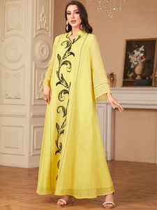 Detail of elegant yellow maxi dress with black floral embroidery and V-neckline texture