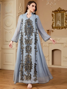 Détail de la broderie complexe noire et dorée sur une robe longue bleu clair