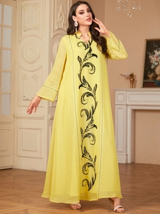 Detailed embroidery of black vines on an elegant yellow Middle Eastern style maxi dress