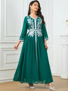 Macro detail of the silver plant leaf embroidery on a dark green elegant long dress