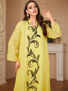 Close-up of elegant black floral embroidery on yellow long-sleeved dress