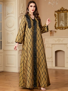 Detail of gold satin maxi dress with black jacquard patterns and sequin embroidery