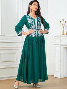 Close-up of intricate silver floral embroidery on a dark green elegant evening gown