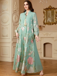 Détails de broderies florales à paillettes vert menthe et pompon sur une robe