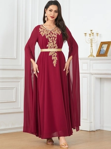 Detail of wine red kaftan dress featuring gold leaf embroidery and split cape sleeves