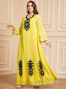 Gros plan sur les broderies noires complexes d'une robe longue bohème jaune vif