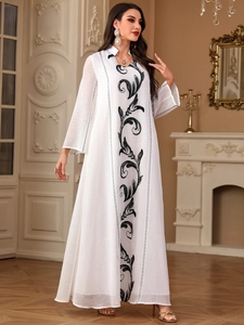 Close-up of elegant white Abaya dress featuring intricate black embroidery and V-neckline