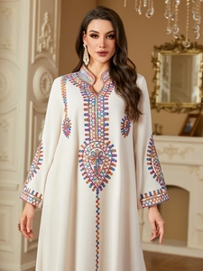 Detail of colorful ethnic embroidery on a cream-colored long-sleeve maxi dress