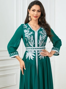 Detailed close-up of intricate silver floral embroidery on a dark green kaftan dress