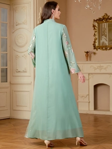Détail de broderie florale à paillettes et franges sur une robe longue vert menthe
