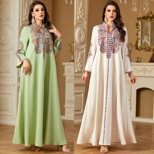 Detail der bunten Paillettenstickerei auf ethnischen Kaftan-Maxikleidern in Creme und Grün