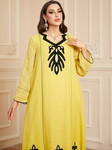Détails de broderie noire sur une robe caftan jaune à manches longues en lin mélangé