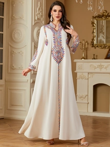 Detailed colorful embroidery on the collar and chest of an elegant cream kaftan dress
