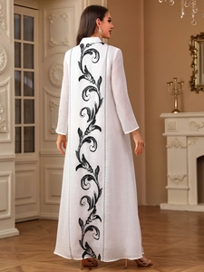 Detailed embroidery of black vine patterns on the back of a white modest maxi dress
