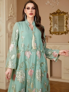 Détail de broderie à paillettes et pompons sur une robe longue abaya vert menthe
