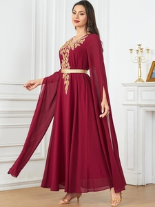 Macro detail of gold leaf embroidery and golden belt on a burgundy chiffon gown