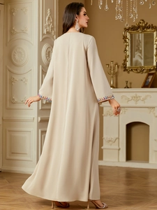 Detail of colorful ethnic embroidery and sequins on sleeve of beige elegant long abaya dress