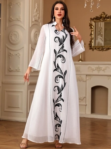 Detailed embroidery of black floral vine patterns on white elegant abaya dress