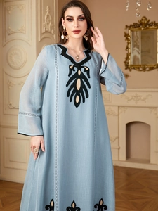 Détails de broderies ethniques complexes sur une robe kaftan bleu clair à manches longues