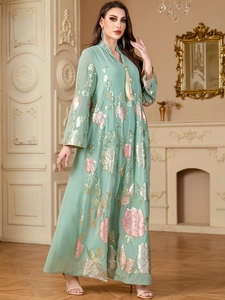 Détail du caftan vert clair avec broderie de paillettes florales et encolure à glands