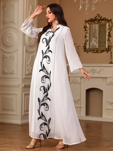 Detail of elegant white maxi dress featuring intricate black vintage floral embroidery