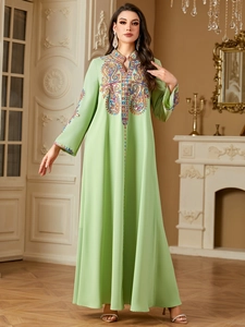 Detailaufnahme bunter Stickereien auf einem luxuriösen mintgrünen Langarm-Kaftankleid