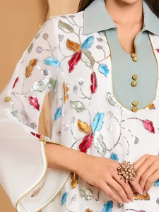 Detailed close-up of intricate floral embroidery and sequins on white georgette tunic