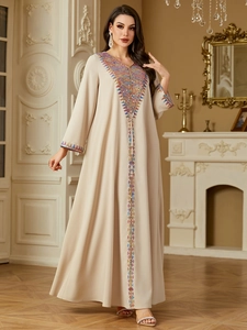 Detail of colorful embroidery and sequins on a beige long kaftan dress with ethnic patterns