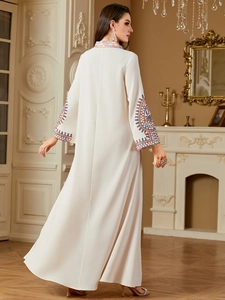 Ethnic white maxi dress with colorful geometric embroidery in elegant classical interior