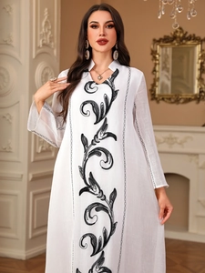 Detail of elegant white long robe featuring intricate black floral embroidery on the neckline
