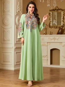 Detail von eleganten Pailletten und Stickereien an einem langärmeligen hellgrünen Kaftan