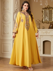 Ethnic yellow kaftan dress with intricate embroidery and long sleeves in elegant interior