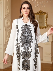 Détails de broderie sur une robe blanche à manches longues avec motifs ethniques dorés