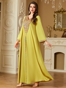 Close-up of ethnic V-neck embroidery and sequin details on a long kaftan dress