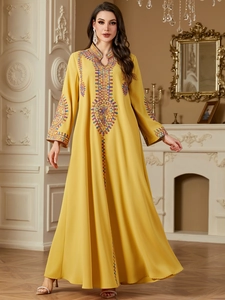 Detail of yellow kaftan dress featuring colorful geometric embroidery and sequins on cuffs