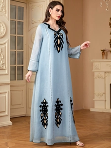 Détail de la robe longue bleu clair avec broderies ethniques noires et dorées à l'ourlet