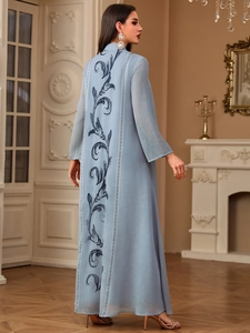 Close-up of deep blue floral embroidery and geometric ribbon on light blue elegant abaya