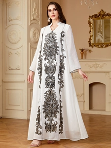 Broderie détaillée aux motifs noir et or sur une robe longue bohème blanche à col en V