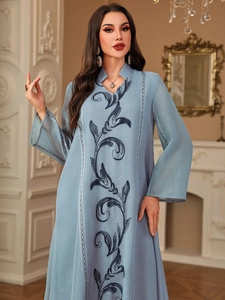 Detail of blue cotton-linen dress with navy floral embroidery and elegant V-neckline