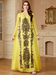Détails de broderies baroques marron et sequins sur une robe longue de couleur jaune vif