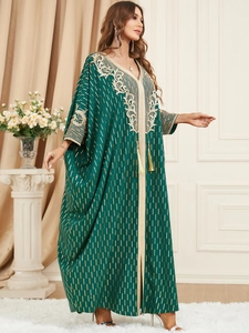 Deep green kaftan with gold line patterns, white lace embroidery, and tassel accents