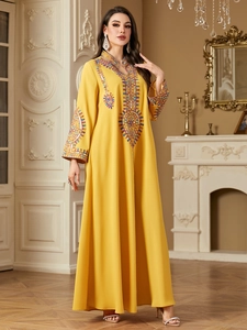Close-up of bohemian yellow kaftan dress with colorful embroidery and sequin details