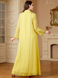 Détail d'une robe abaya jaune à manches longues avec broderie noire dans le dos